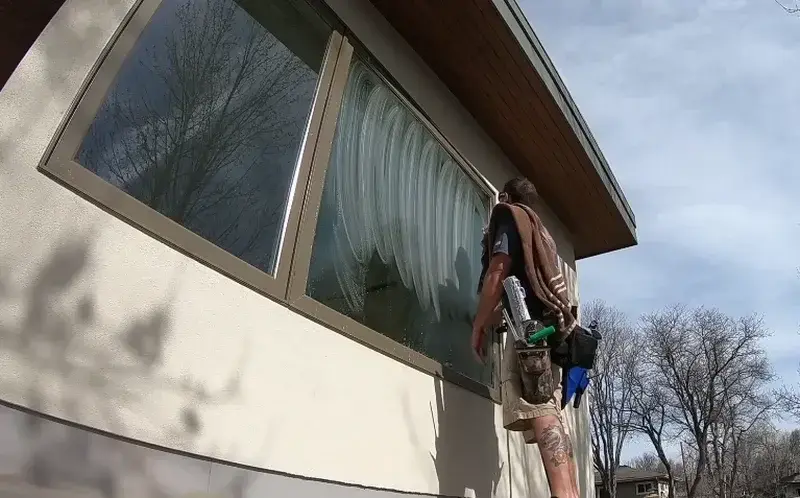 Professional exterior window cleaner working on a large residential window