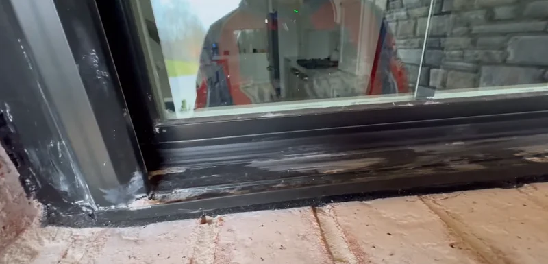 Technician assessing markings and residue on a window during construction cleanup