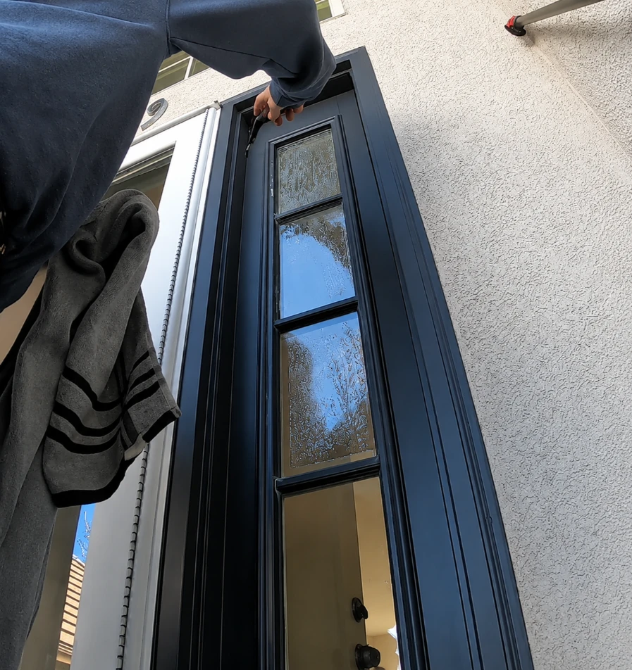 Cleaner detailing a narrow residential door window