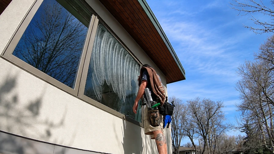 Professional cleaner washing a large residential window